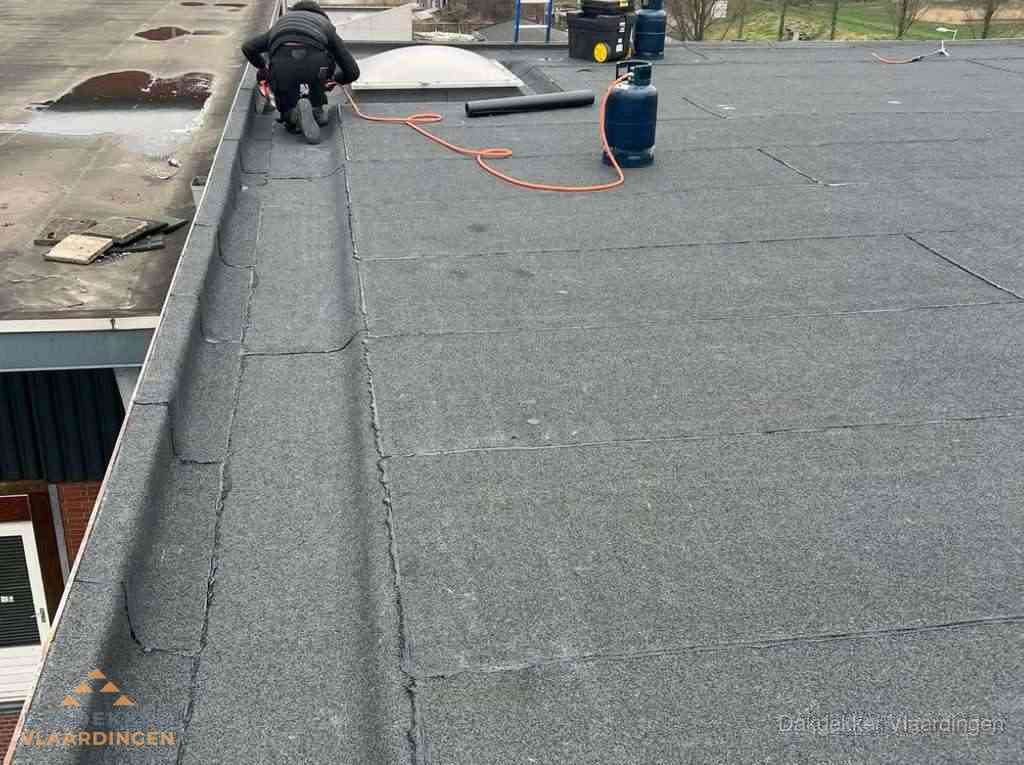 Dakdekker repareert bitumen dakbedekking op groot plat dak in Vlaardingen Dakdekker repareert bitumen dakbedekking op groot plat dak in Vlaardingen