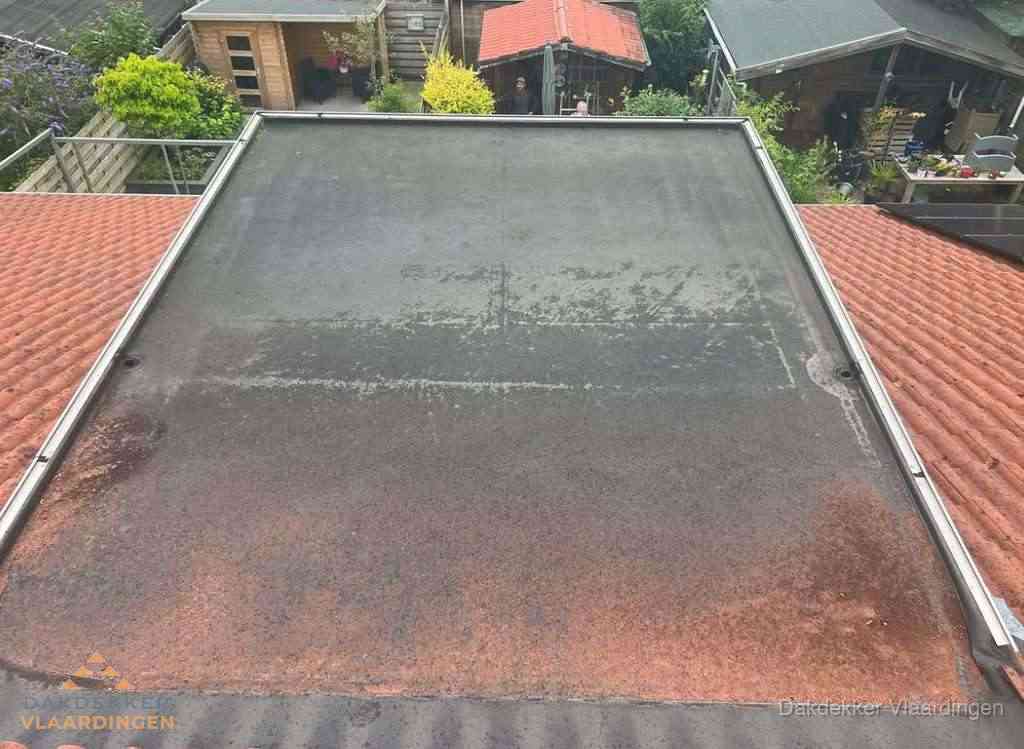 Verouderd plat dak met slijtage tussen schuine daken in Vlaardingen Verouderd plat dak met slijtage tussen schuine daken in Vlaardingen